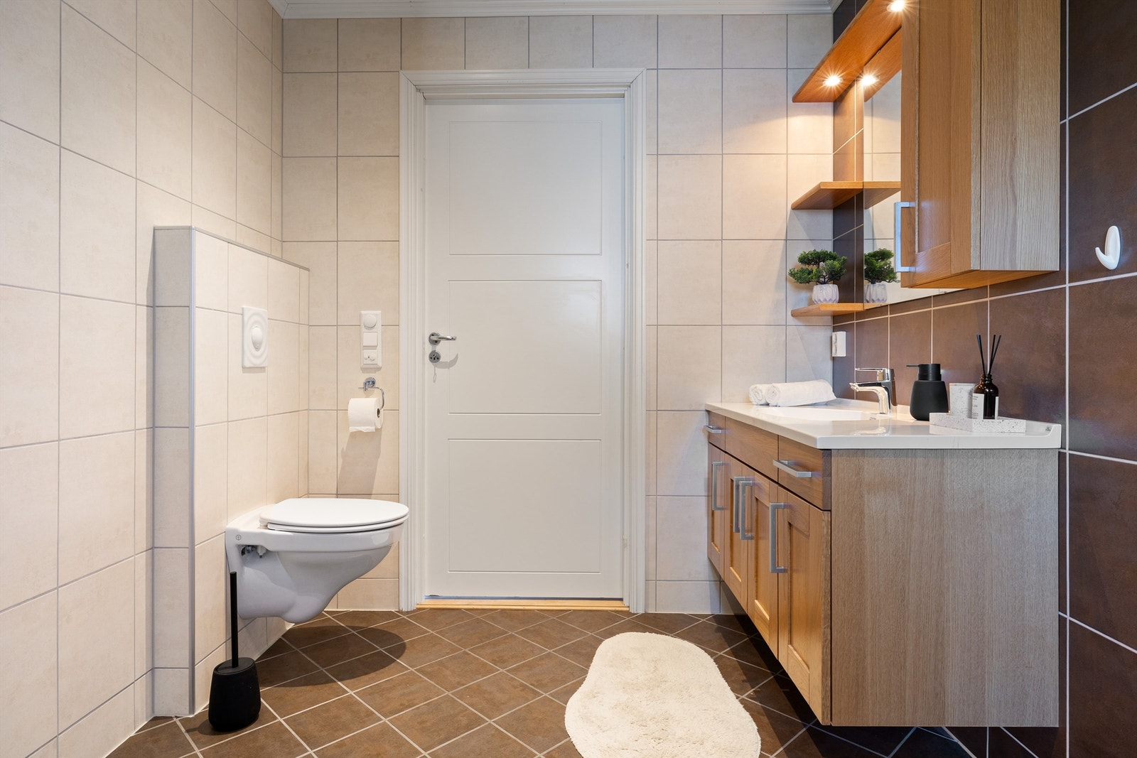 Badet er flislagt med varmekabler i gulv og spotter i tak Galleribilde
