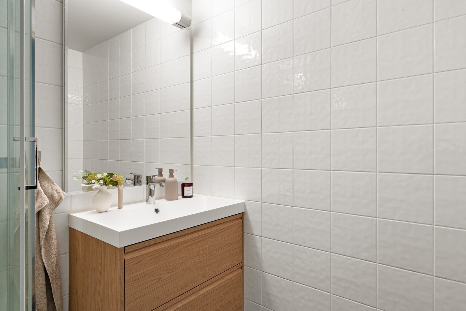 Badet er flislagt med lyse veggflater og mørke gulvfliser med varme i gulv som skaper et moderne og tidløst uttrykk. Galleribilde