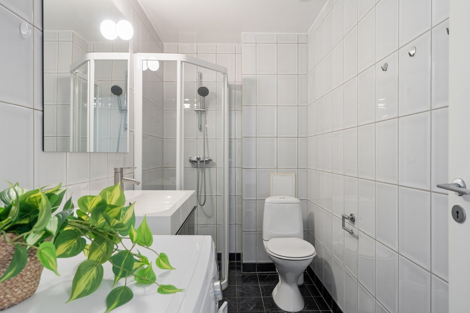 Badet er flislagt og utstyrt med dusjvegger. Opplegg for vaskermaskin Galleribilde