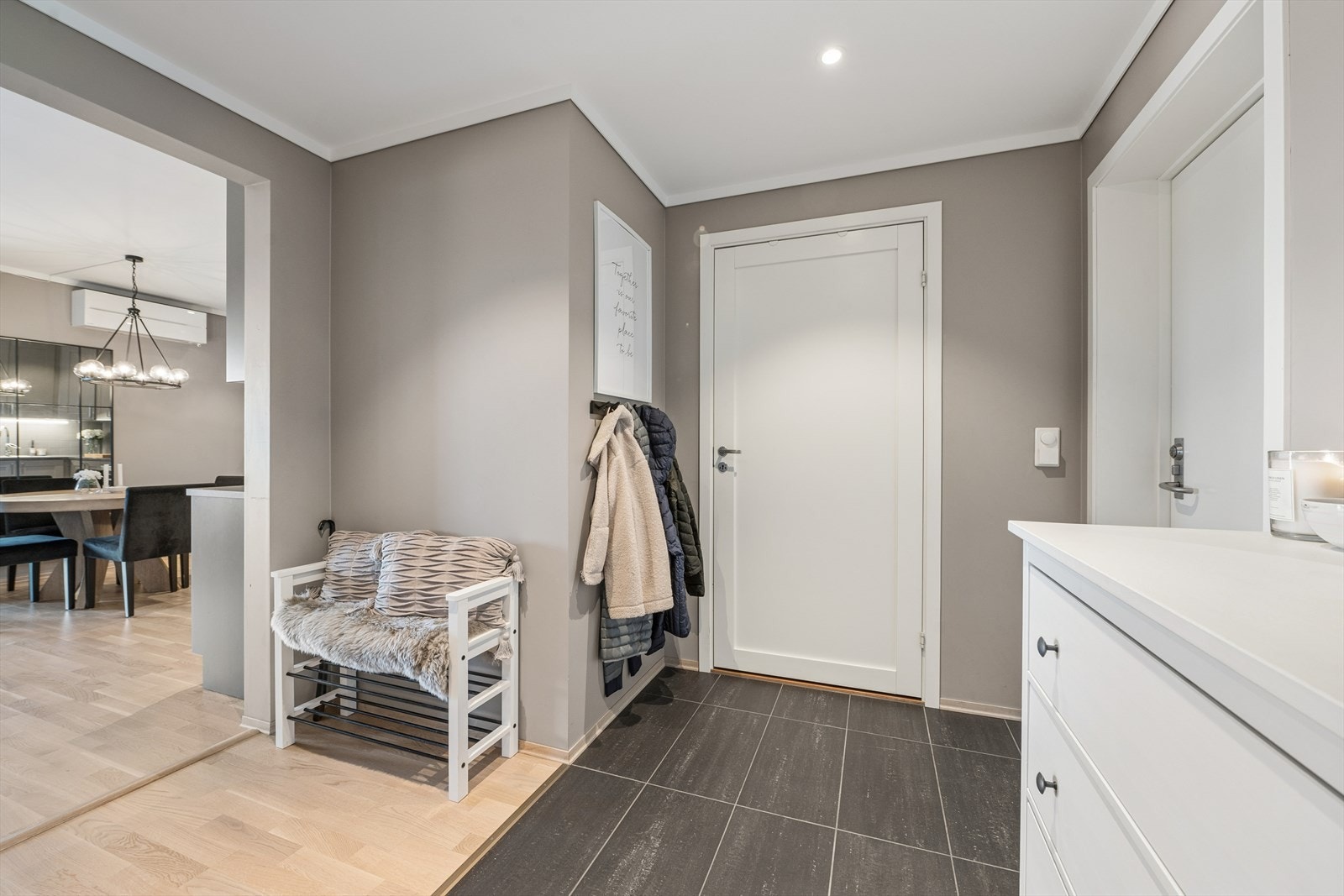 Innenfor inngangsdøren ønskes du velkommen til en romslig og moderne entré. Her er det lekkert flislagt gulv med varmekabler, lyse og tidsriktige fargevalg på vegger og tak, samt downlights i himling som gir behagelig belysning. Galleribilde
