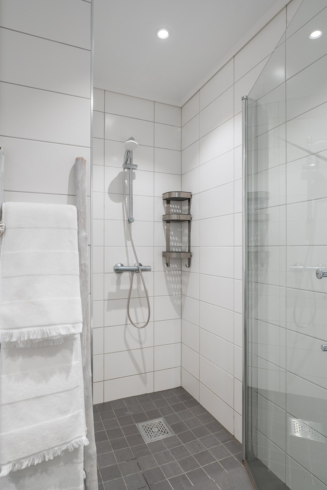 Videre er det en romslig dusjnisje med glassdører, downlights i tak og opplegg for vaskemaskin. Badet fremstår som helhetlig, lyst og innbydende - et perfekt sted å starte dagen. Galleribilde