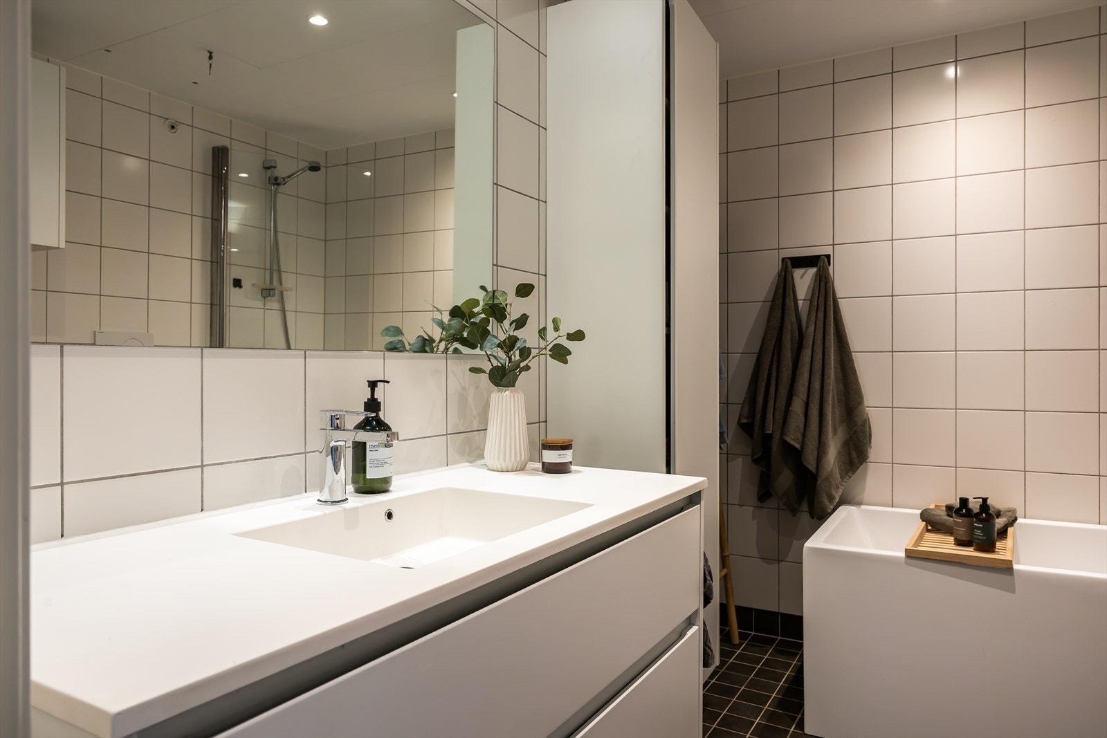 Oppgradert baderomsinnredning med servant av corian, badekar og praktisk benk i heltre eik. Galleribilde
