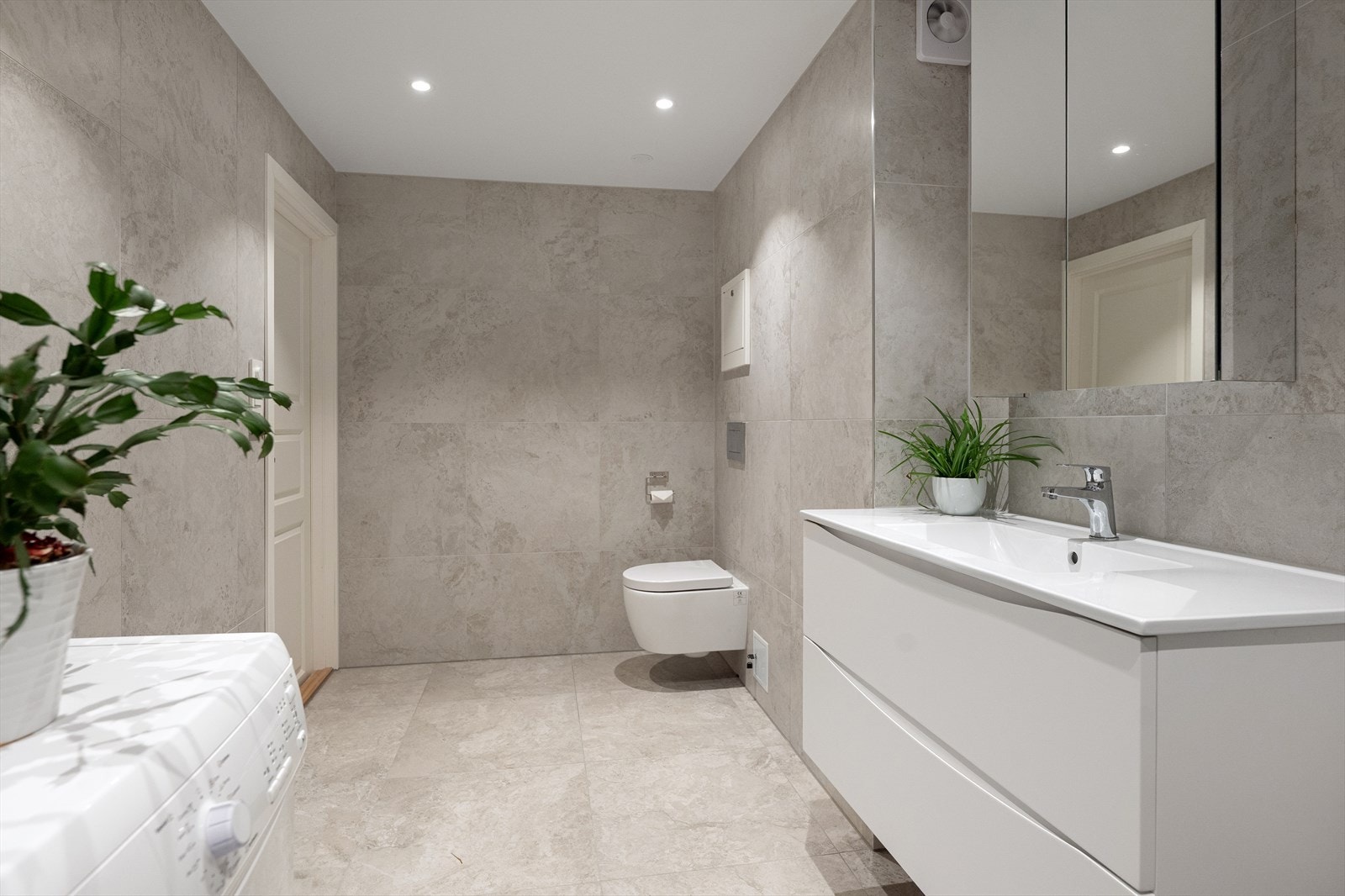 Badet er innredet med moderne servantskap med nedfelt servant, speilskap med integrert belysning samt vegghengt klosett med innebygget sisterne. Galleribilde