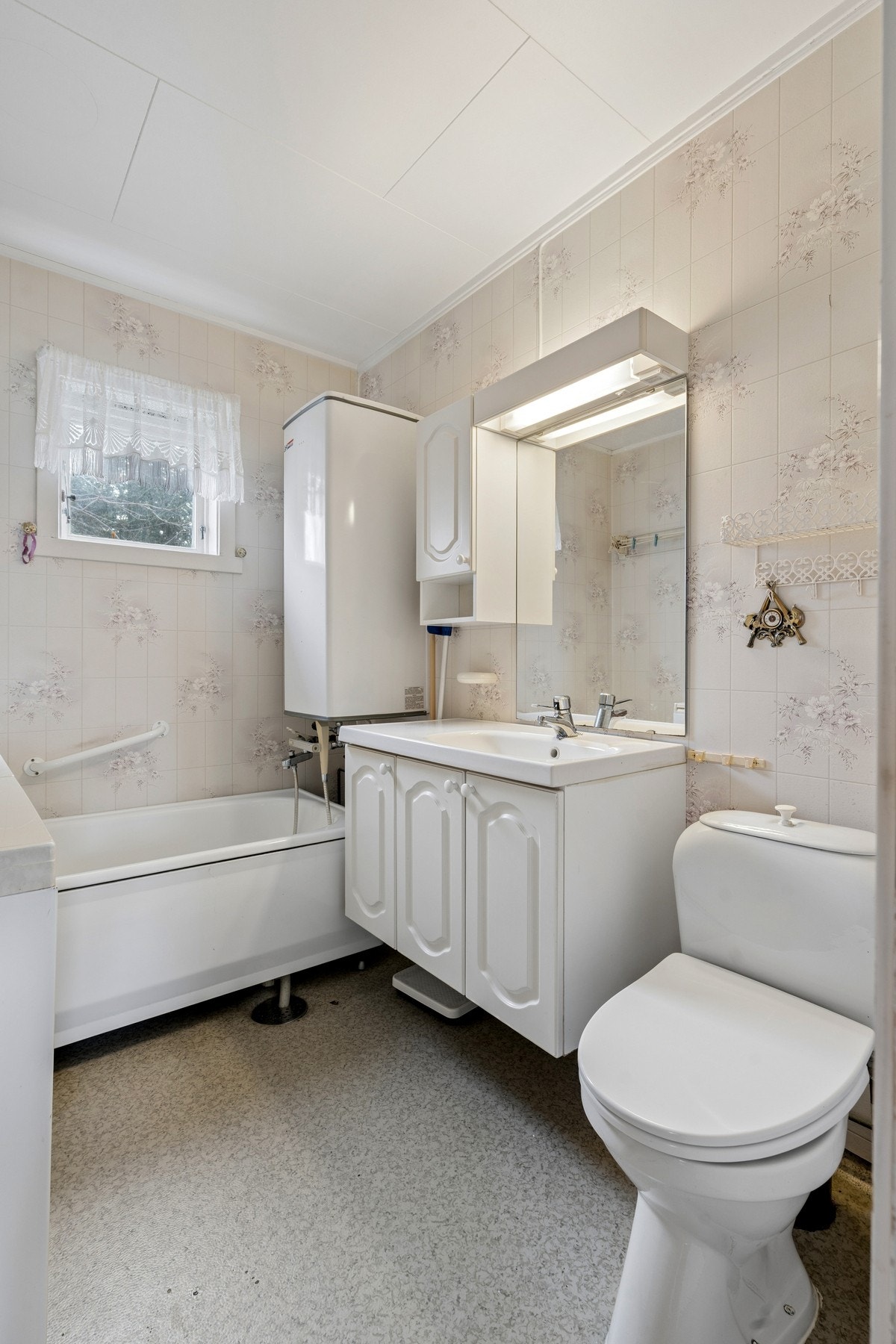 Badet er innredet med badekar, gulvmontert toalett og servant med ett-greps blandebatteri. Galleribilde