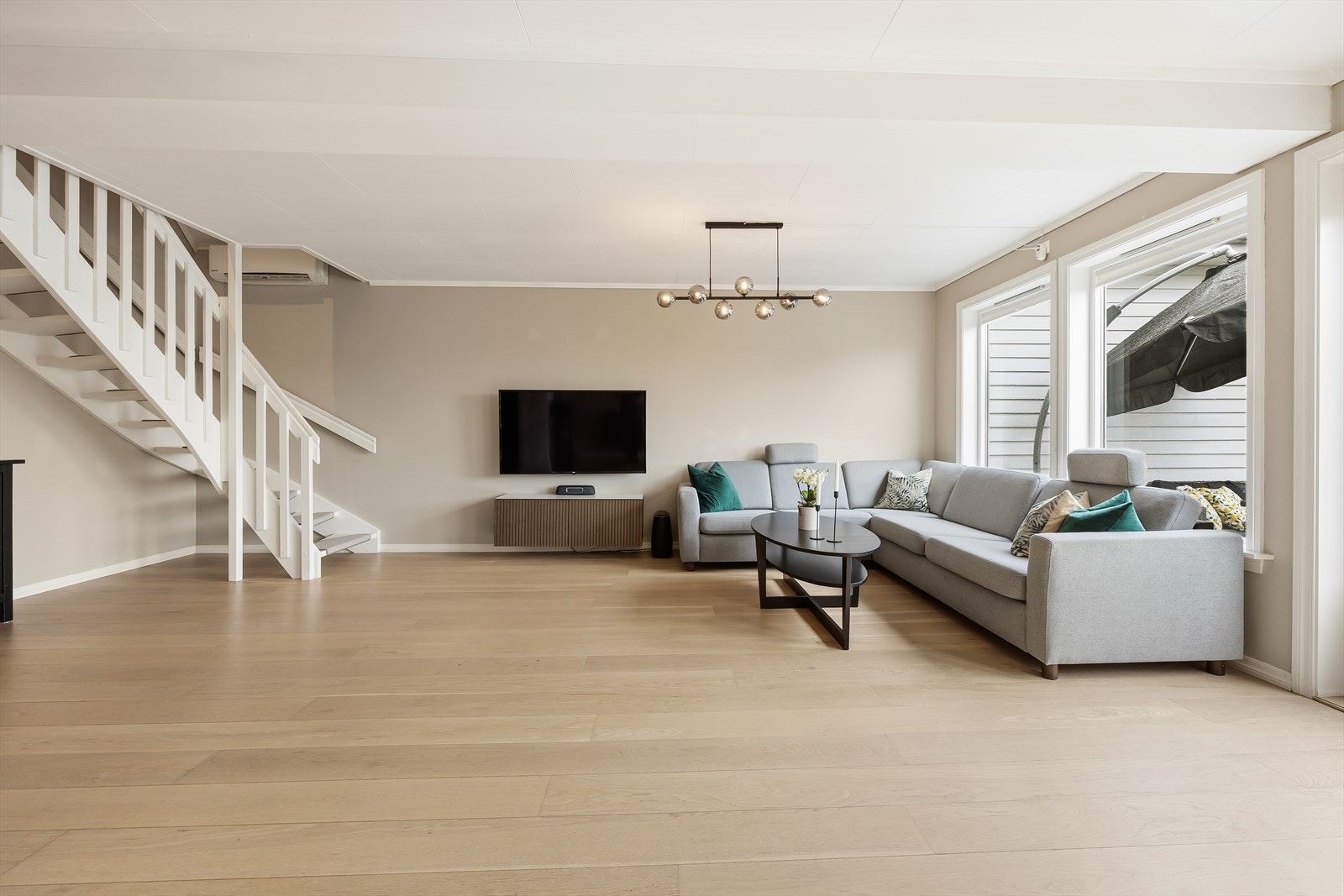 Romslig stue med god plass til en stor sofagruppe. Den malte tretrappen leder opp til loftsetasjen. Galleribilde