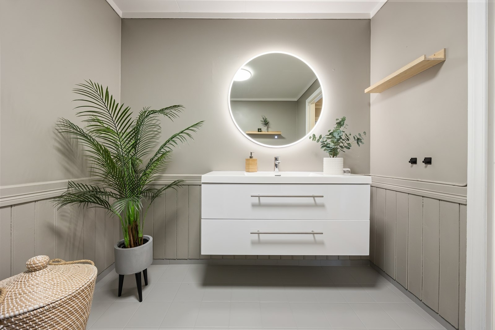 Badet i første etasje har flislagt gulv med varmekabler og servant med møblement. Galleribilde