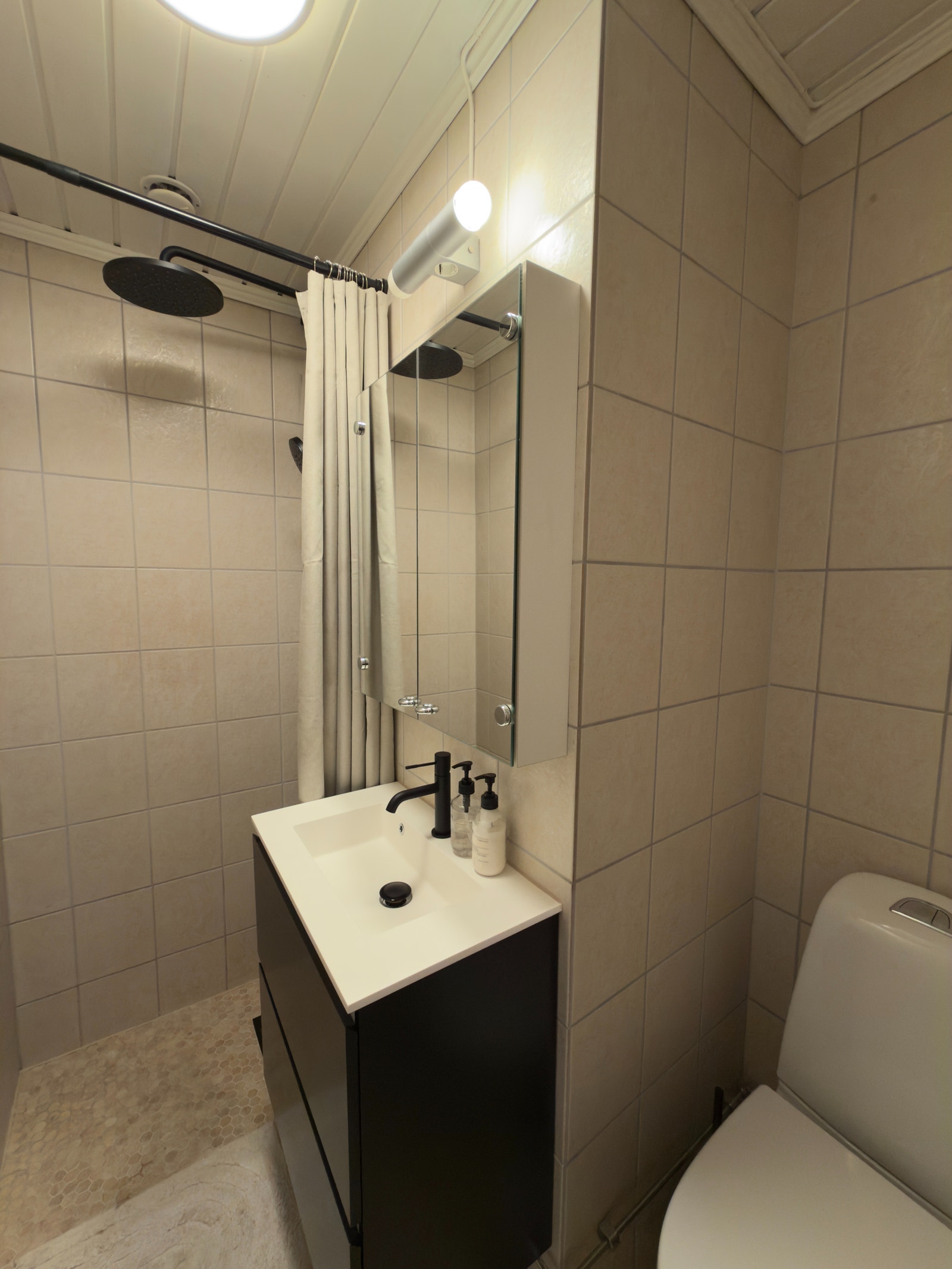 Adgang til bad direkte fra gang. Badet ble pusset opp i 2025. Det ble lagt nye fliser på gulv, nytt lys, toalett, servantskap og dusj ble montert. Galleribilde