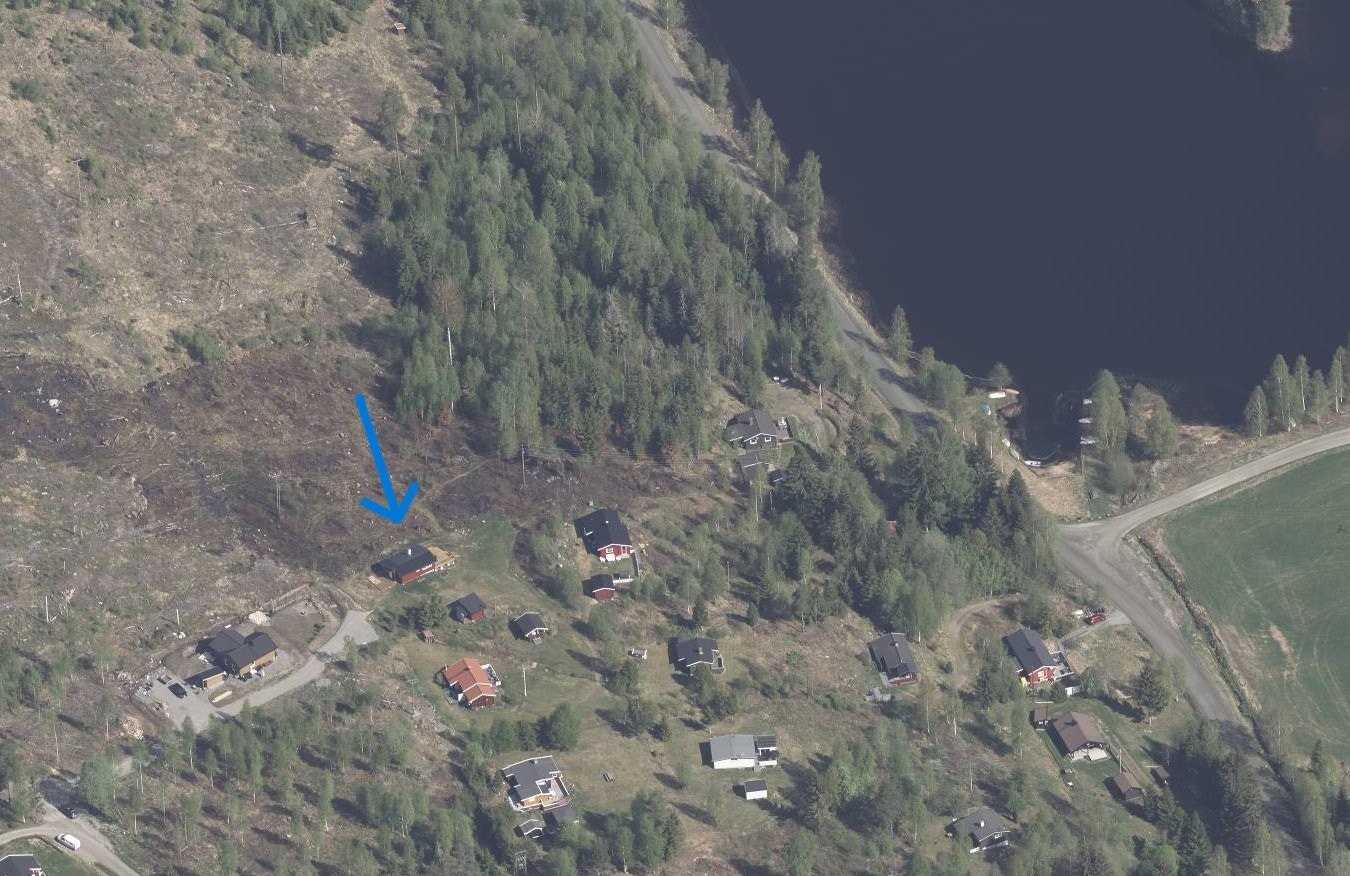 Flyfoto over deler av hyttefeltet og Dølisjøen. Blå pil mot hytta. Hentet fra 1881.no. Galleribilde