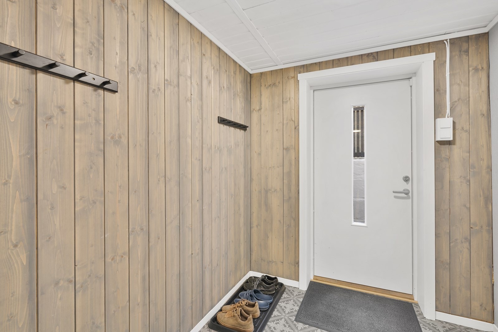 Entréen i kjelleren har panel på veggene og plass til å henge fra seg yttertøy. Galleribilde