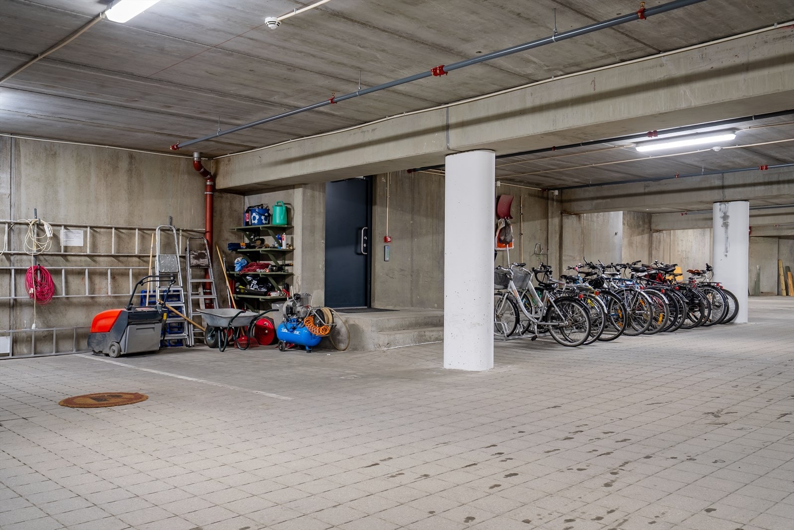 Til venstre er garasjens to verkstedplasser for bilvask, dekkskift m.m. Til høyre vises en av flere innendørs sykkelparkeringer, med direkte tilgang til felles avfallsbrønner Galleribilde