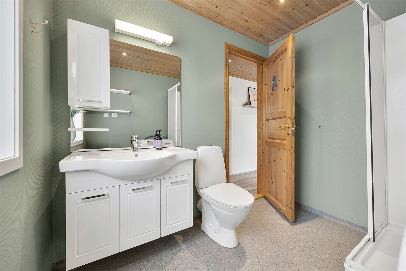 Badet har vinylbelagt gulv med gulvvarme. Det er malt tapet på vegger og panel på innvendig tak. Galleribilde