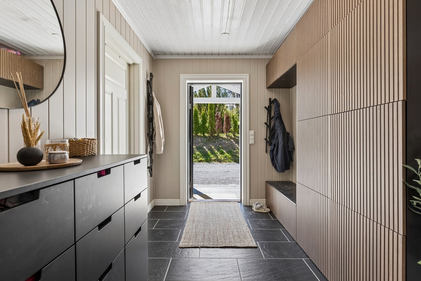 Entréen er både romslig og praktisk, med flislagt gulv med gulvvarme og en lekker garderobeløsning med spiler. Galleribilde