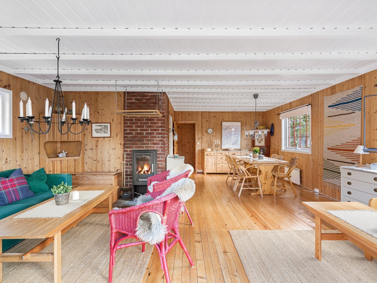 Det åpne allrommet er hyttas samlingspunkt, med furugulv og en sentralt plassert vedovn for varme og hygge. Galleribilde