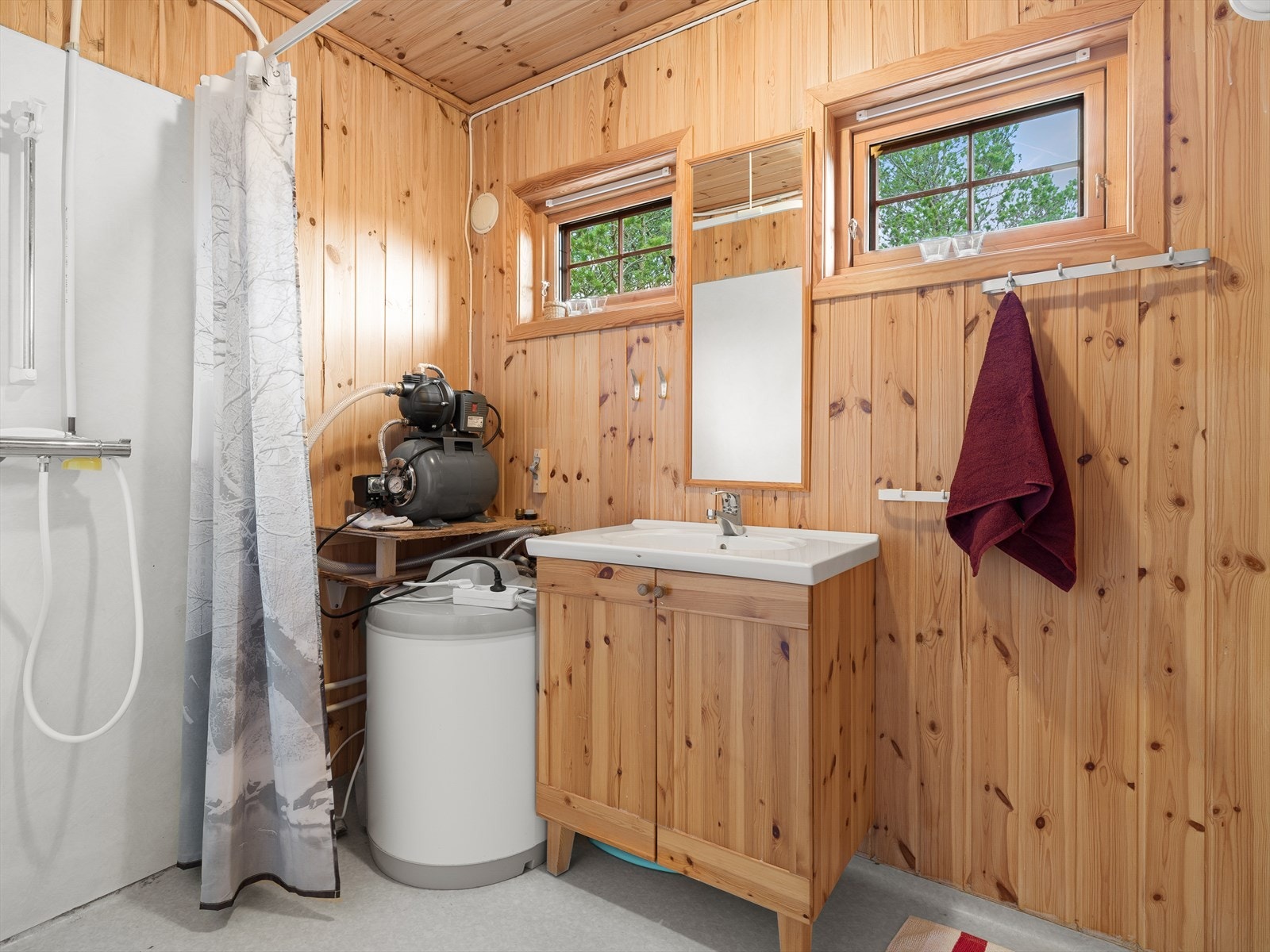 Badet har vinylbelegg på gulv, trepanel på veggene og er utstyrt med servant, dusjløsning og en 120-liters varmtvannstank. Galleribilde