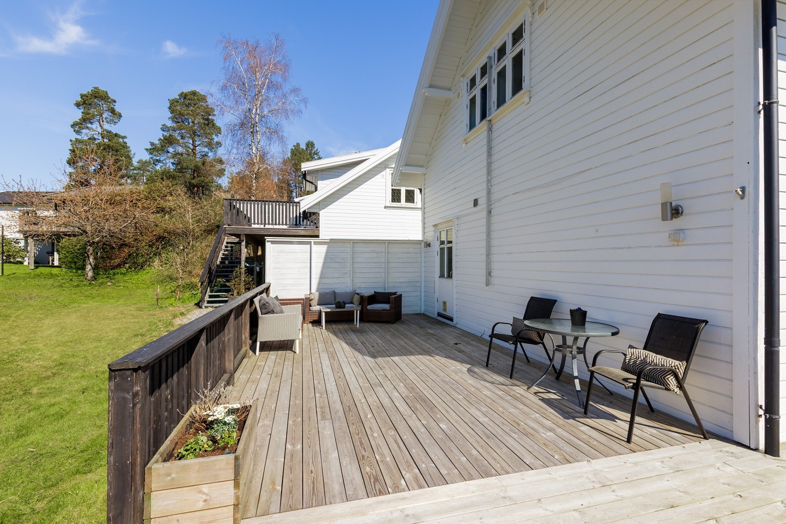 En solrik og romslig terrasse som strekker seg rundt halve boligen. Galleribilde