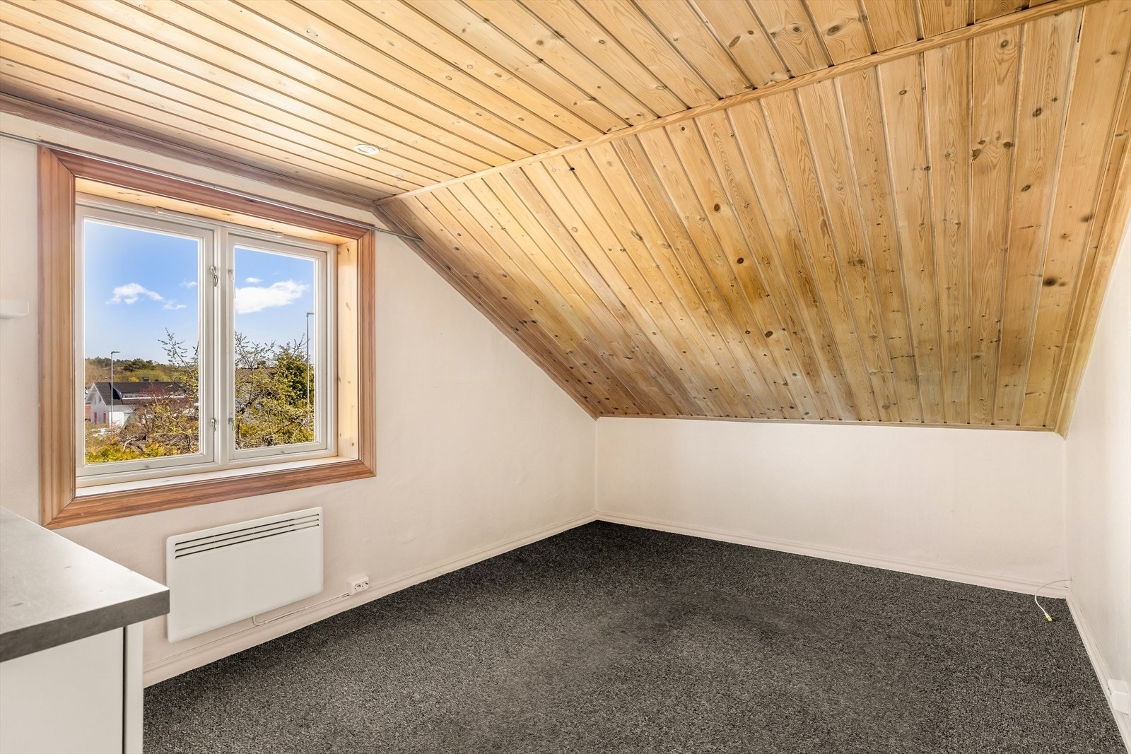 Det ene soverommet i andre etasje har teppe på gulvet og skråtak. Galleribilde