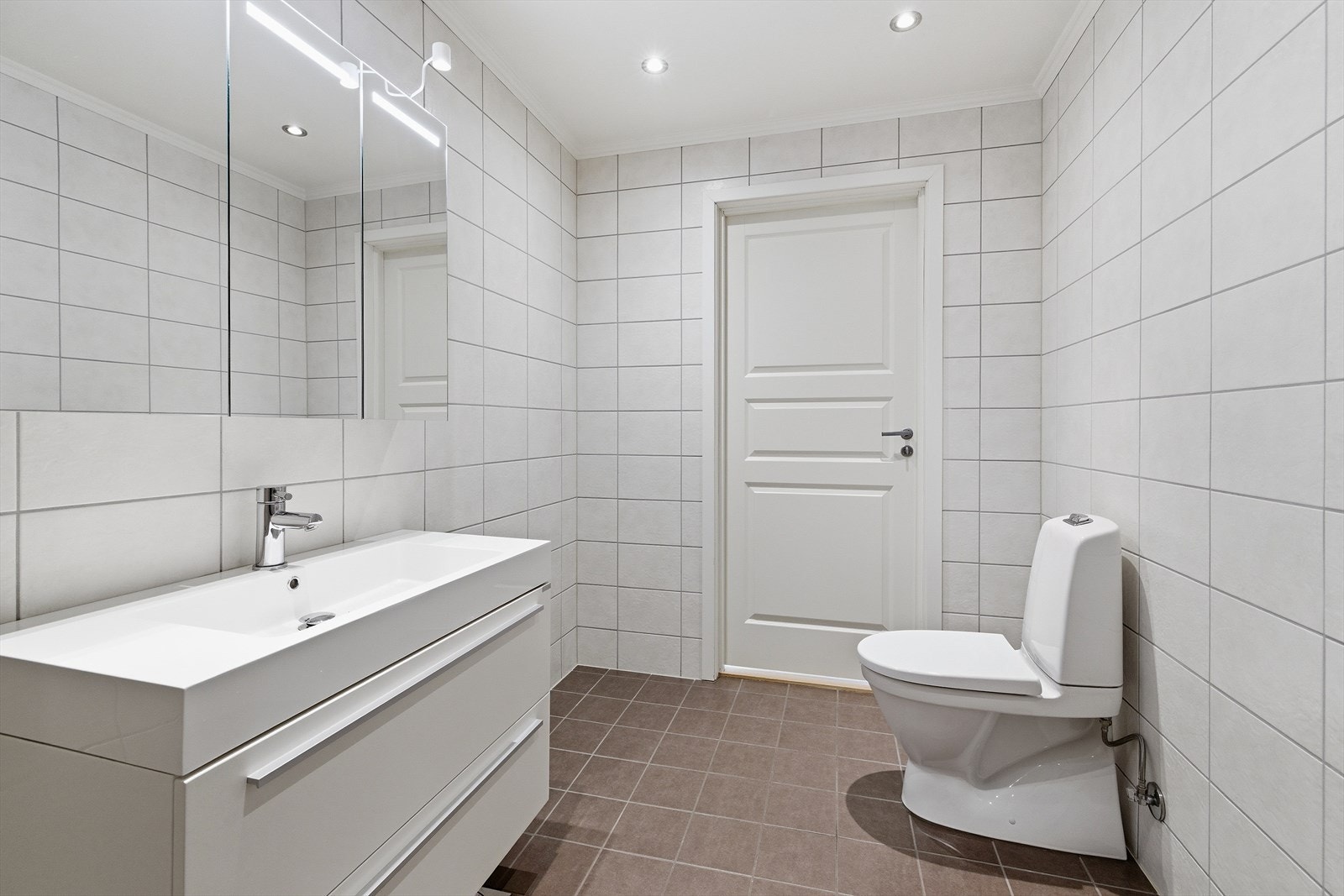 Badet er helfliset og har en moderne innredning med vegghengt toalett og praktisk servantmøbel. Galleribilde