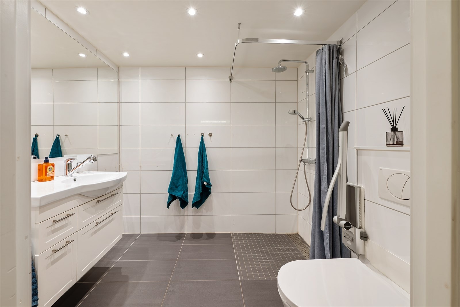 Pent og moderne, flislagt bad med en tidløs utførelse. Badet er romslig utformet og har en praktisk planløsning med god plass til både dusjsone og innredning. Galleribilde