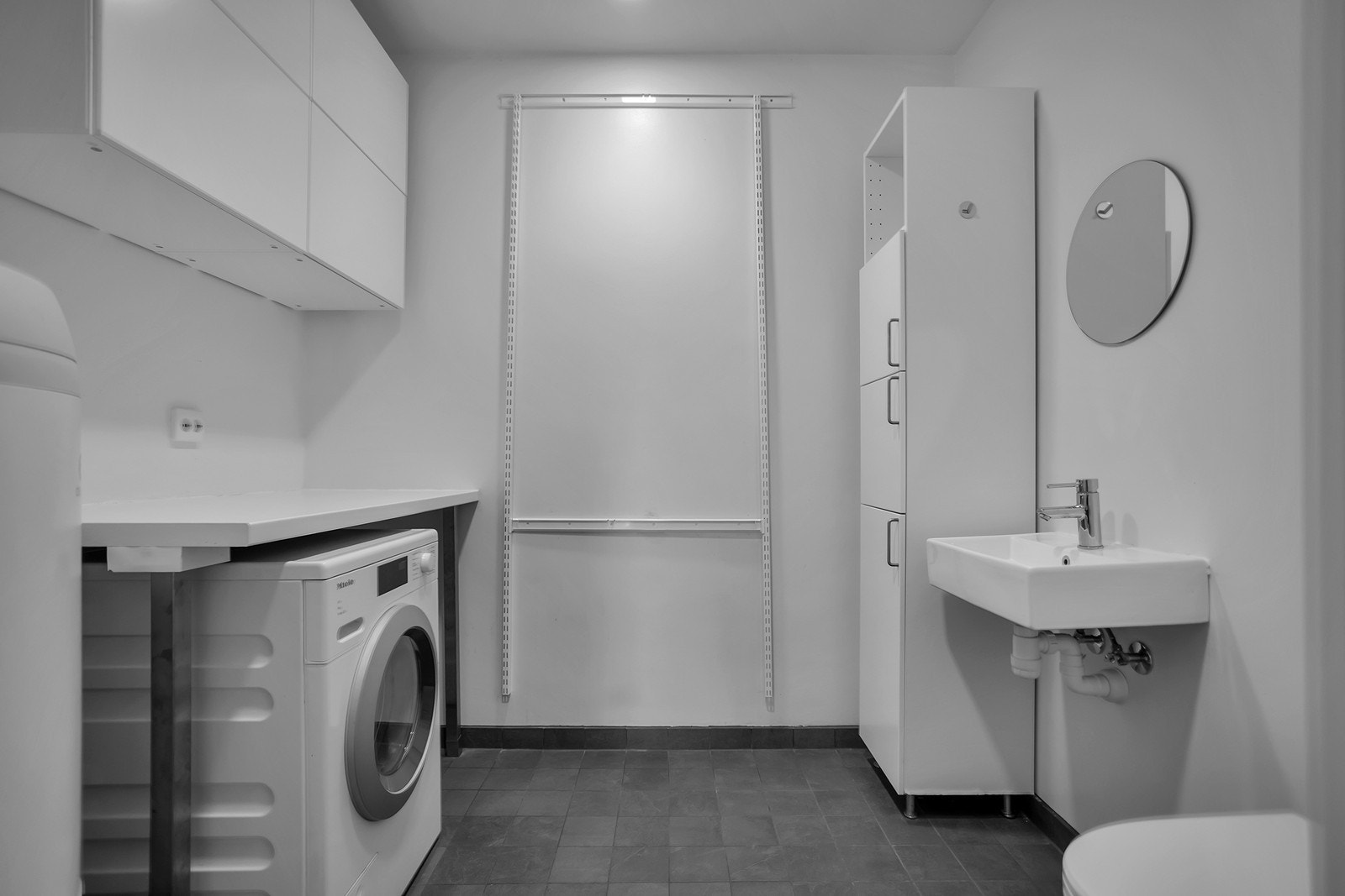 Praktisk vaskerom med innredning, gode oppbevaringsmuligheter, toalett og plass til vaskemaskin og tørketrommel. Galleribilde