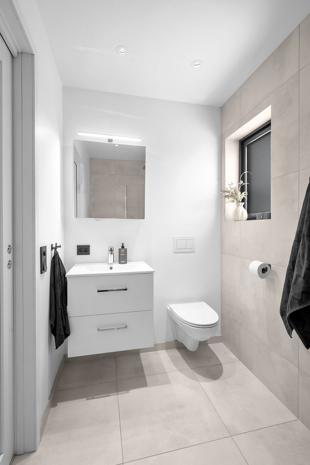 Badet tilknyttet soverommet har store fliser på gulv og delvis vegg. Det er vannbåren gulvvarme på badet. Galleribilde
