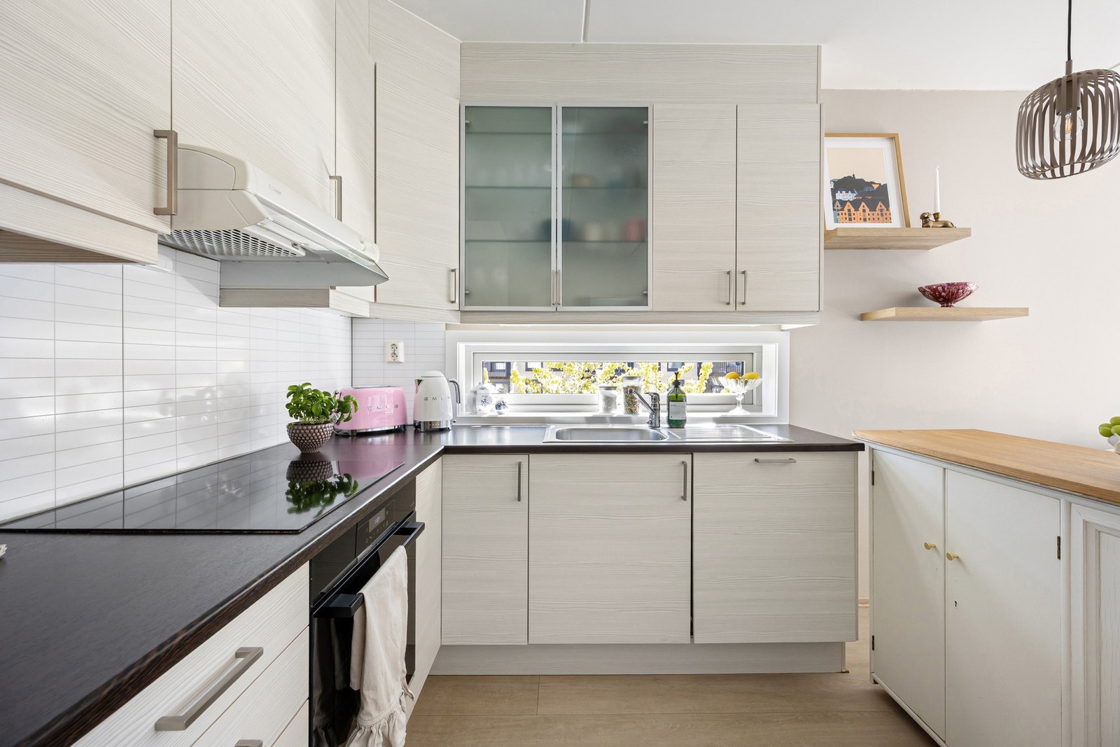 Innredningen har fronter i hvit utførelse, benkeplate av laminat og nedfelt kjøkkenvask med armatur. Galleribilde