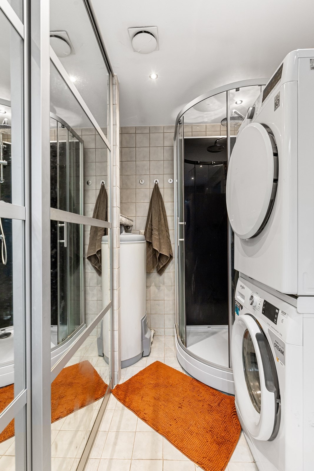 Videre er badet utstyrt med dusjkabinett, veggmontert wc, naturlig avtrekk og opplegg for vaskemaskin. Her finner du også boligens varmtvannsbereder. Galleribilde
