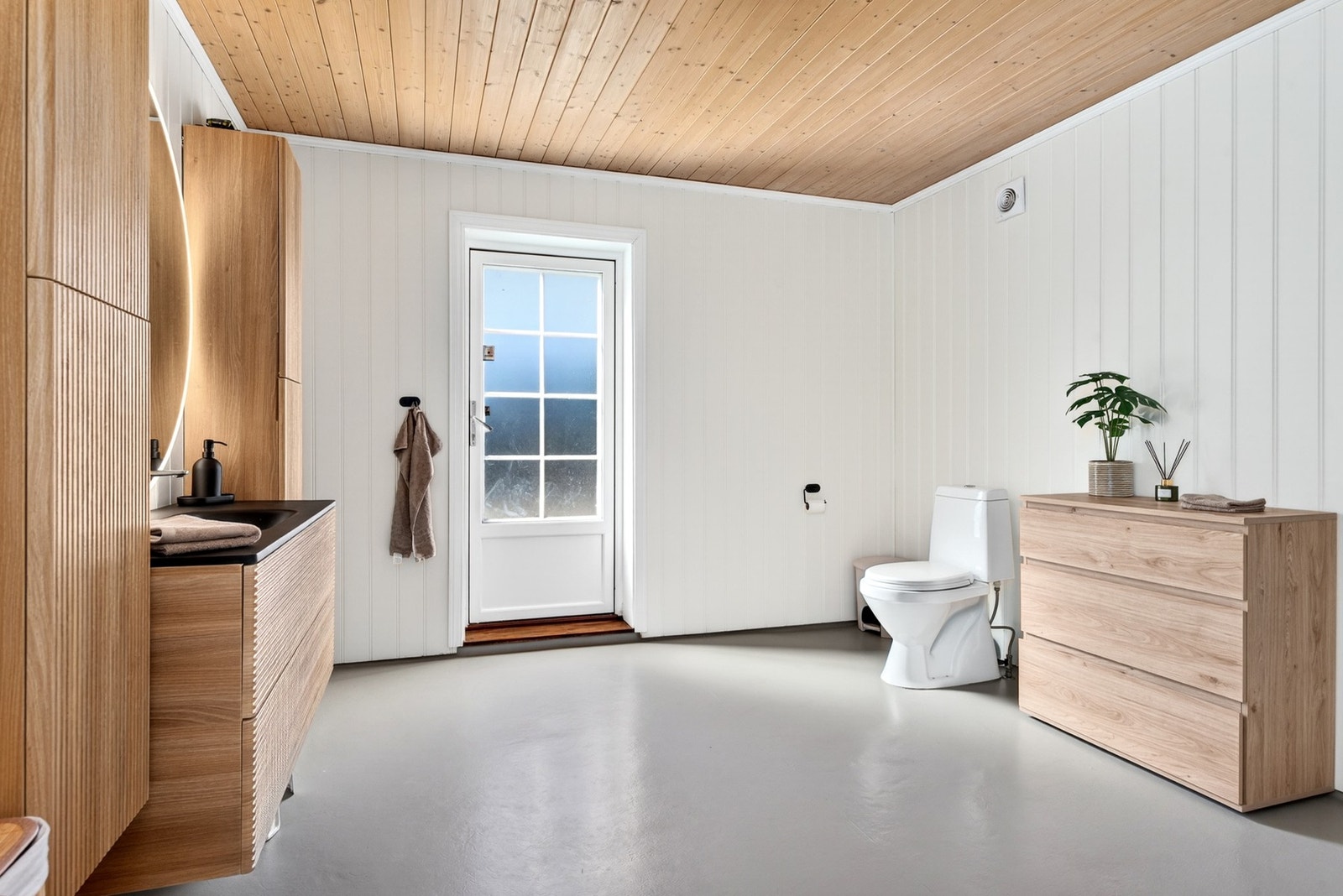 Bad med toalett, dusjkabinett, vegghengt baderomsinnredning og utgang til veranda. Galleribilde