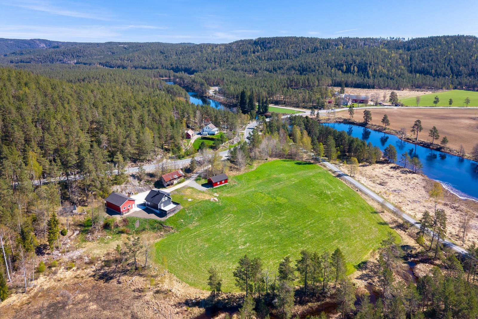 Oversiktsbilde av småbruket med tun, bygninger og omkringliggende landlige omgivelser. Galleribilde