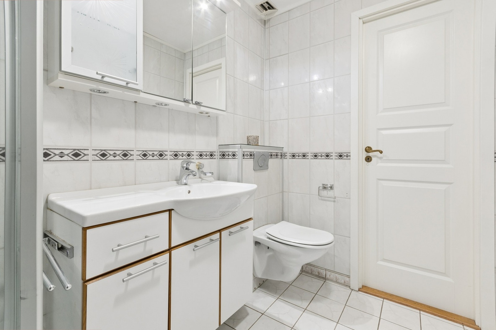 Badet er innredet med nedfelt servant, vegghengt toalett og dusjkabinett. Galleribilde