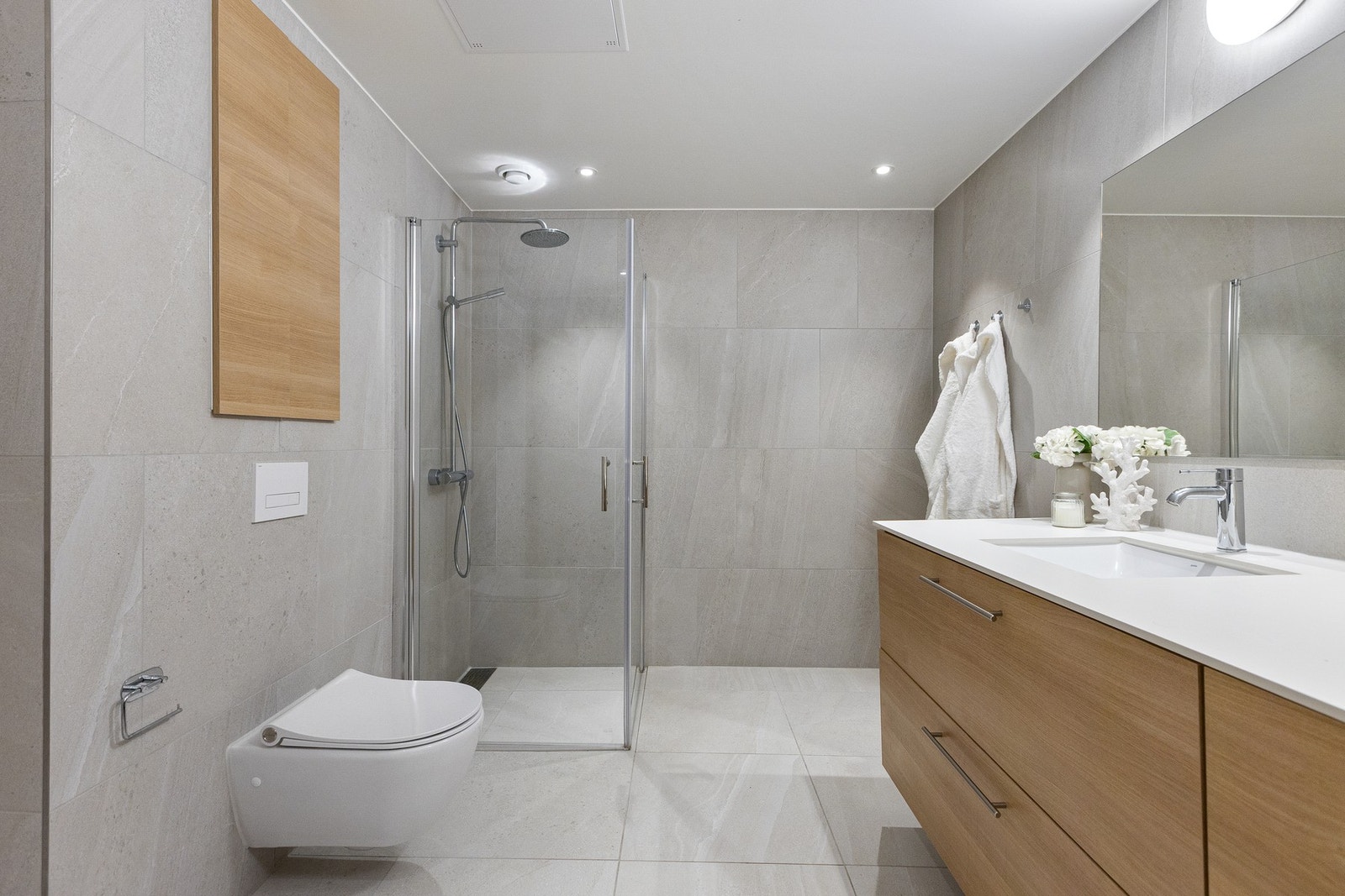Badet har vannbåren gulvvarme som gir god komfort. Innredningen består av baderomsinnredning med to nedfelte servanter, veggmontert toalett og dusjhjørne med glassvegger. Galleribilde