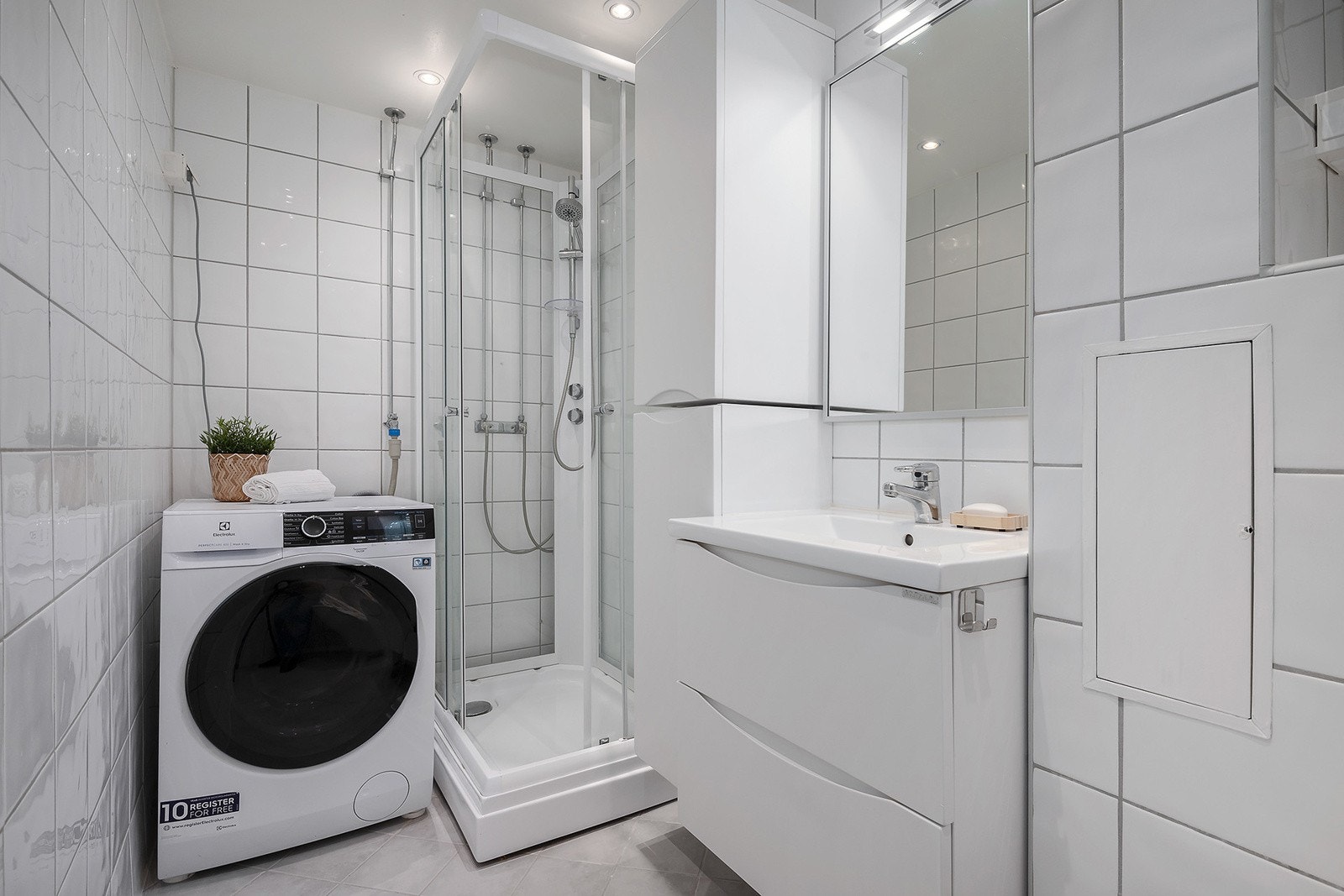 Lyst og flislagt bad med downlights, varmekabler i gulv og opplegg for vaskemaskin. Galleribilde