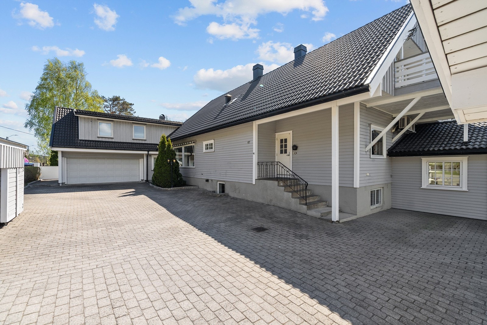 Den store hellebelagte gårdsplassen gir et eksklusivt og ryddig inntrykk, samtidig som den er svært praktisk og lettstelt. Her er det god plass til opptil 7 biler, og området er enkelt å holde rent med minimalt vedlikehold. Galleribilde