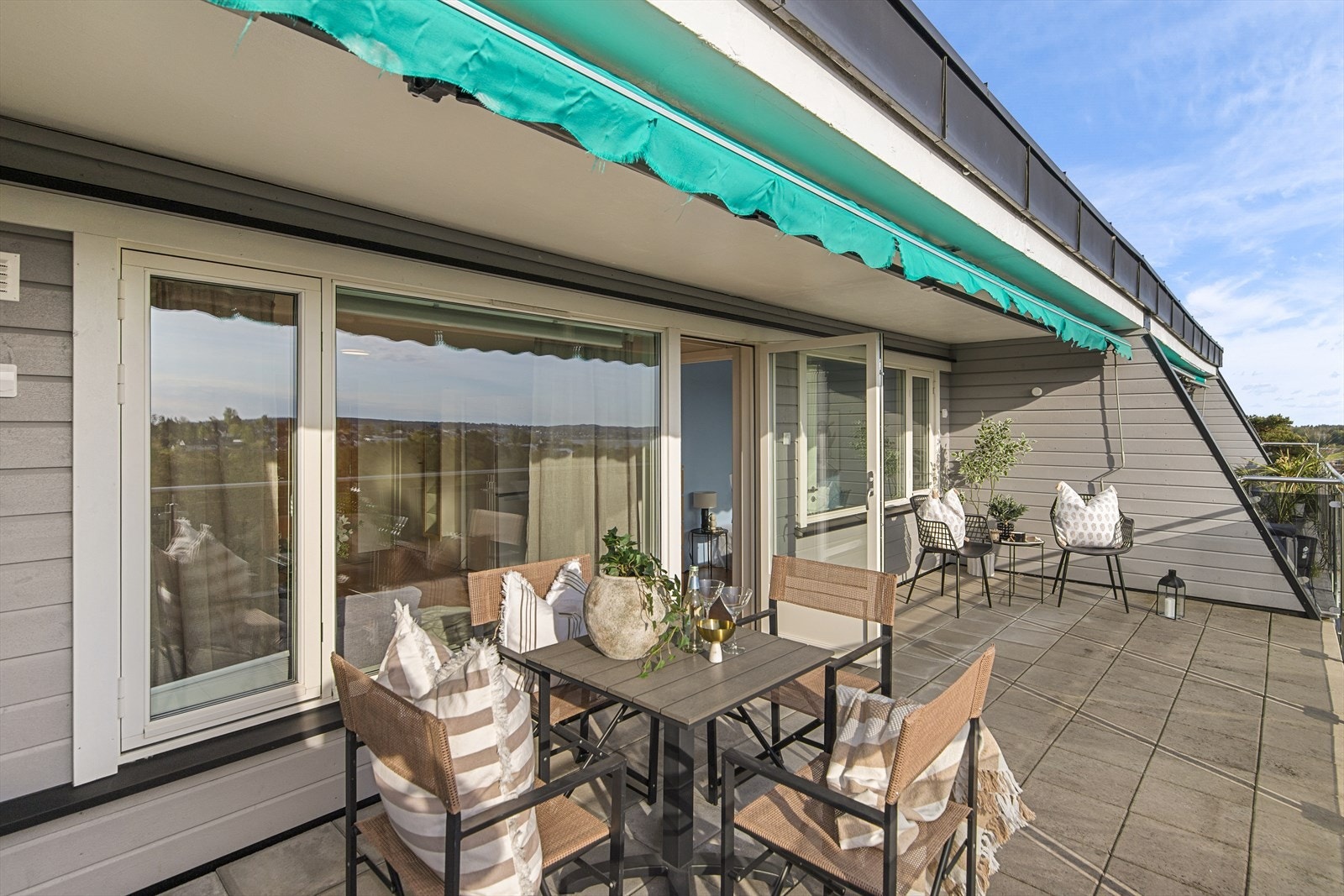Terrassedekket består av steinheller fra 2021, og terrassen rammet inn av glassrekkverk slik at hele utsikten kan nytes Galleribilde