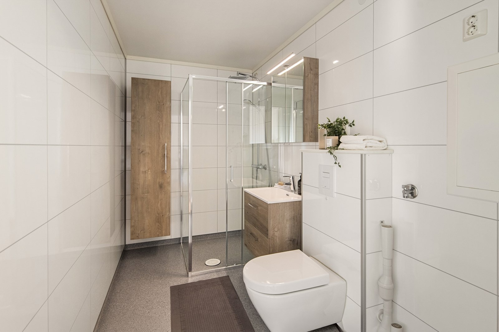 Badet ble renovert i 2019 og fremstår som praktisk og moderne med baderomsplater på vegger og belegg på gulv med gulvvarme Galleribilde