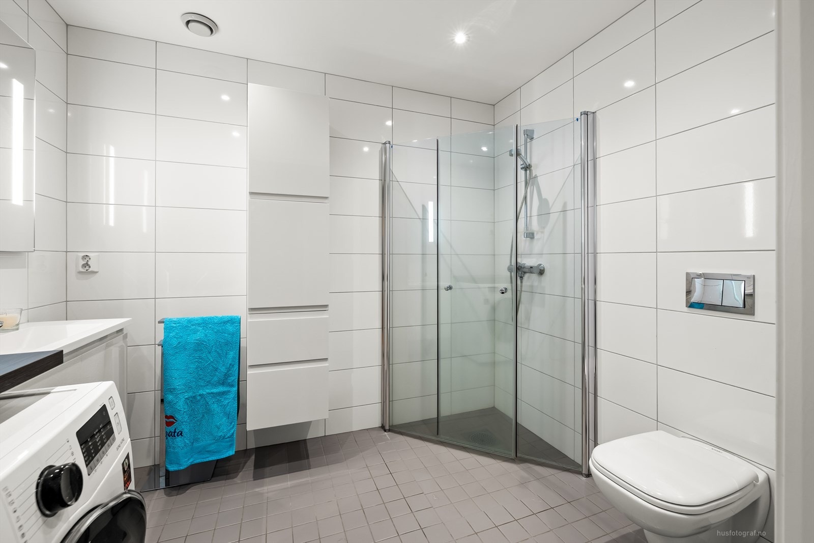 Badet er innredet med nedfelt servant med rom for oppbevaring i underskap, speil med belysning, vegghengt toalett og dusjhjørne. Det er opplegg for vaskemaskin. Galleribilde