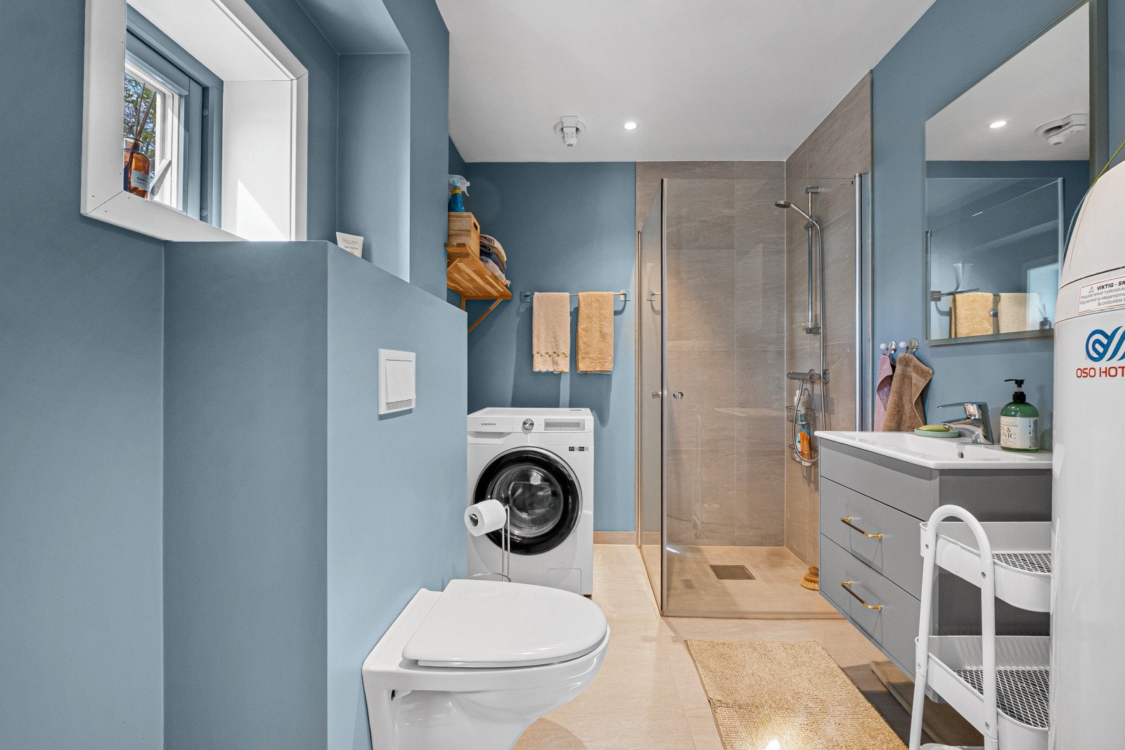Badet er flislagt med gulvvarme og har opplegg for vaskemaskin. Videre er det veggmontert toalett og en elektrisk styrt vifte for god ventilasjon. Galleribilde
