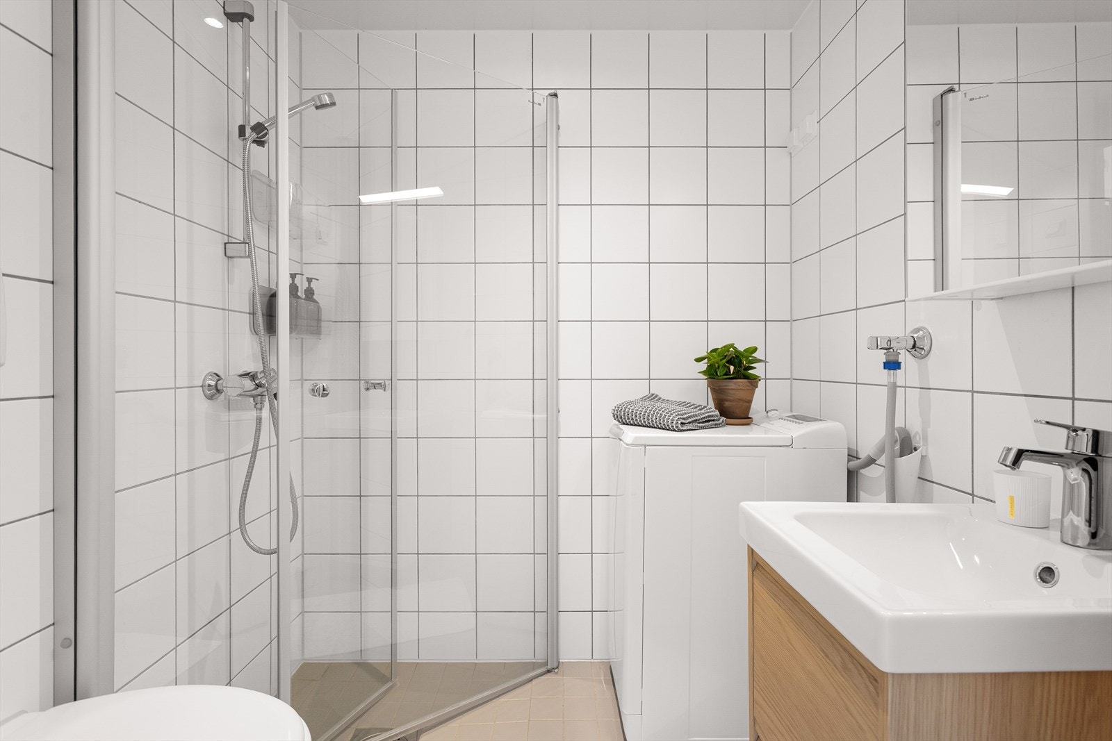 Lys og moderne bad fra 2005 med varmekabler, opplegg for vaskemaskin og downlights i taket. Galleribilde