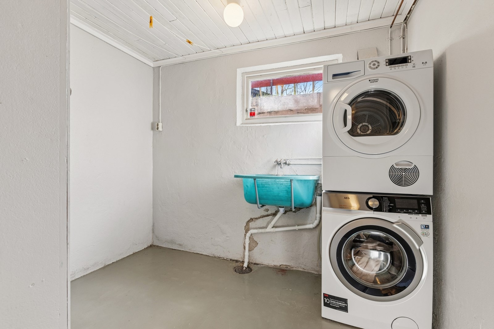 Vaskekjelleren med opplegg for vaskemaskin og en slitt utslagsvask av plast.. Det er ikke fuktsikret på vegger og gulv i rommet. Vegger og gulv i mur. De er malt. Lufteventil i veggen. Det må monteres elektrisk vifte i rommet. Våtrommet må oppgraderes. Galleribilde