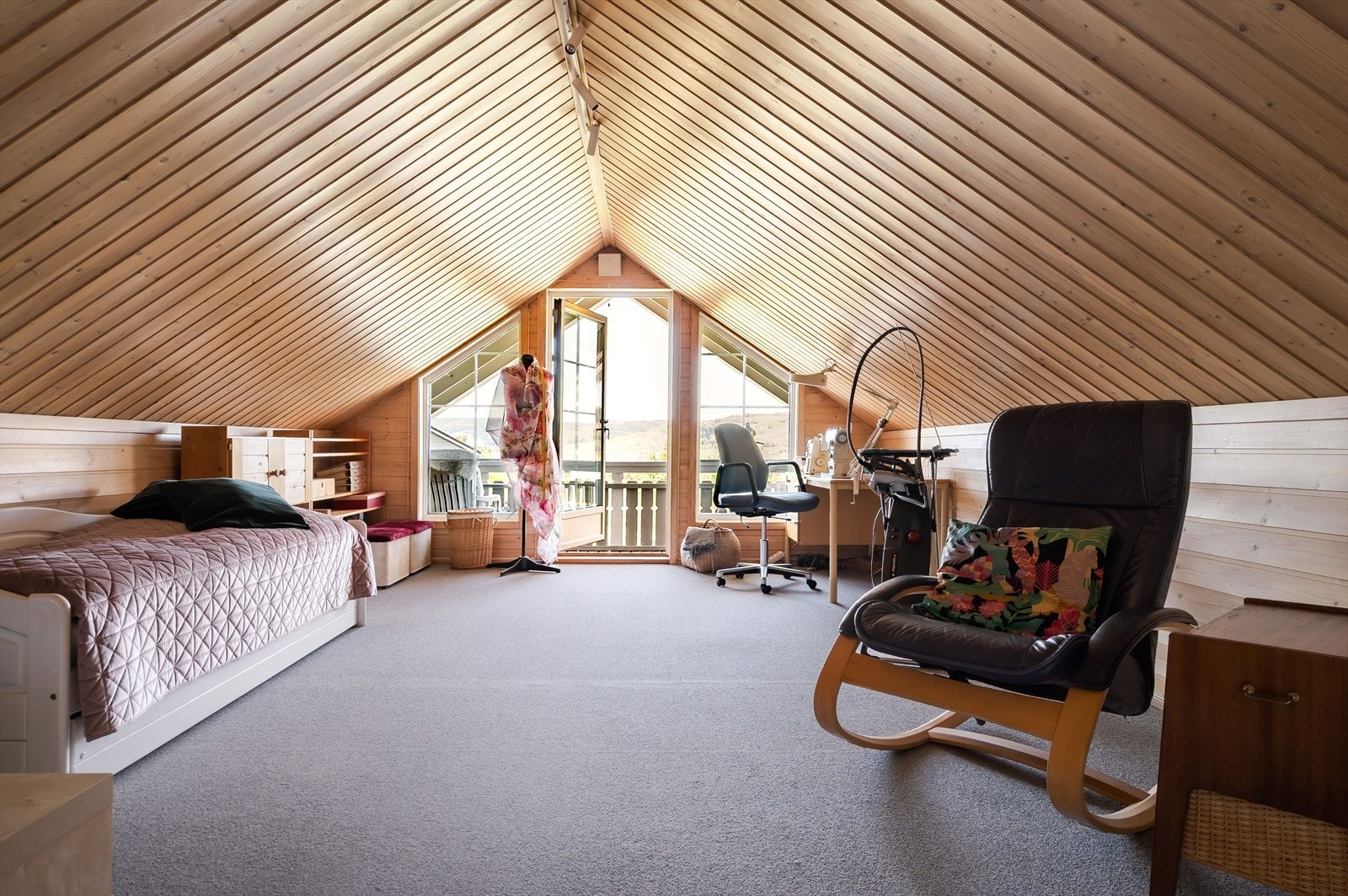 I 2. etasje er det en stor og hyggelig loftstue med lunt teppe på gulv og overflater med trepanel. Galleribilde