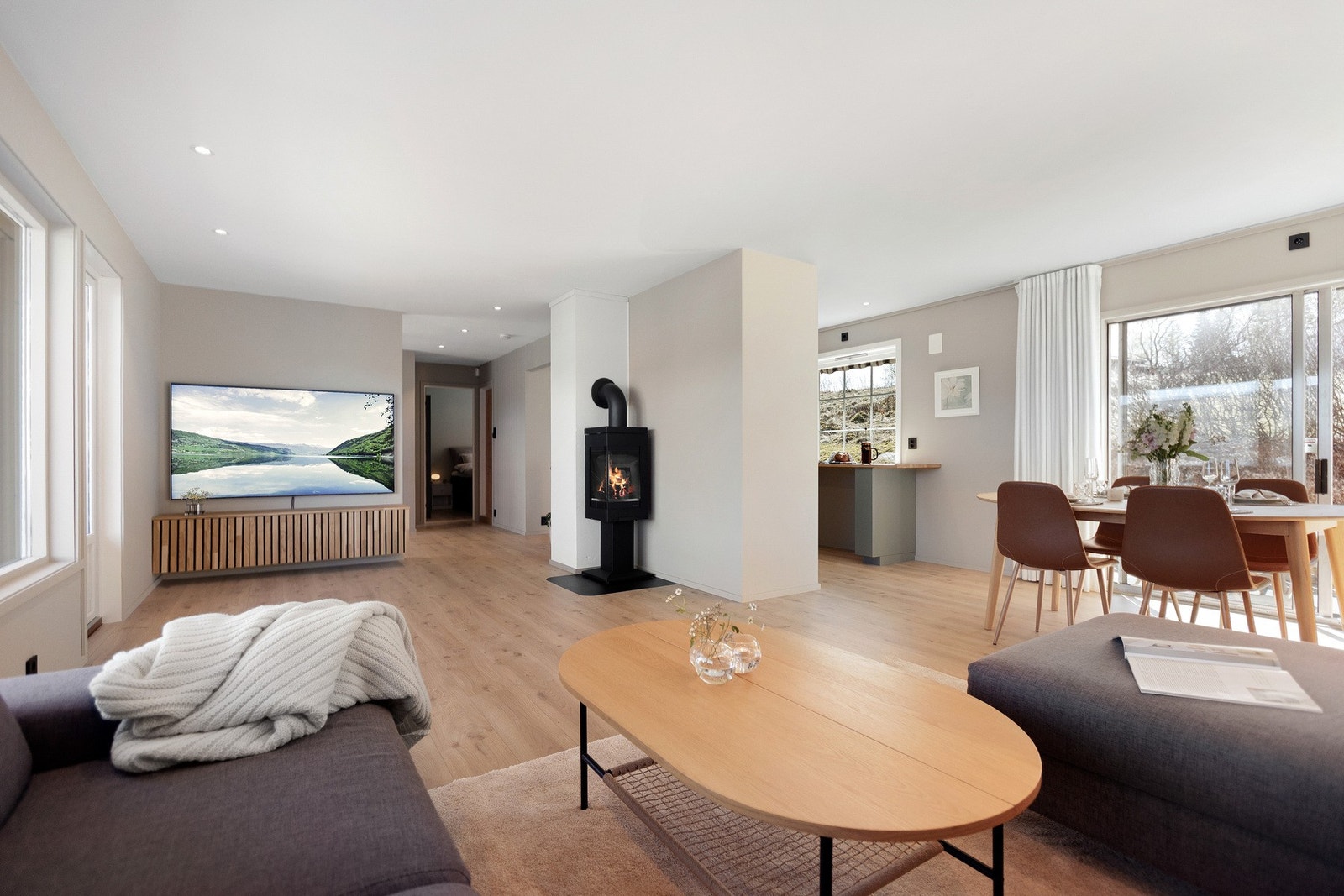 Åpen og luftig stue med moderne peisovn, TV-sone og naturlig inndeling av rommet. Galleribilde