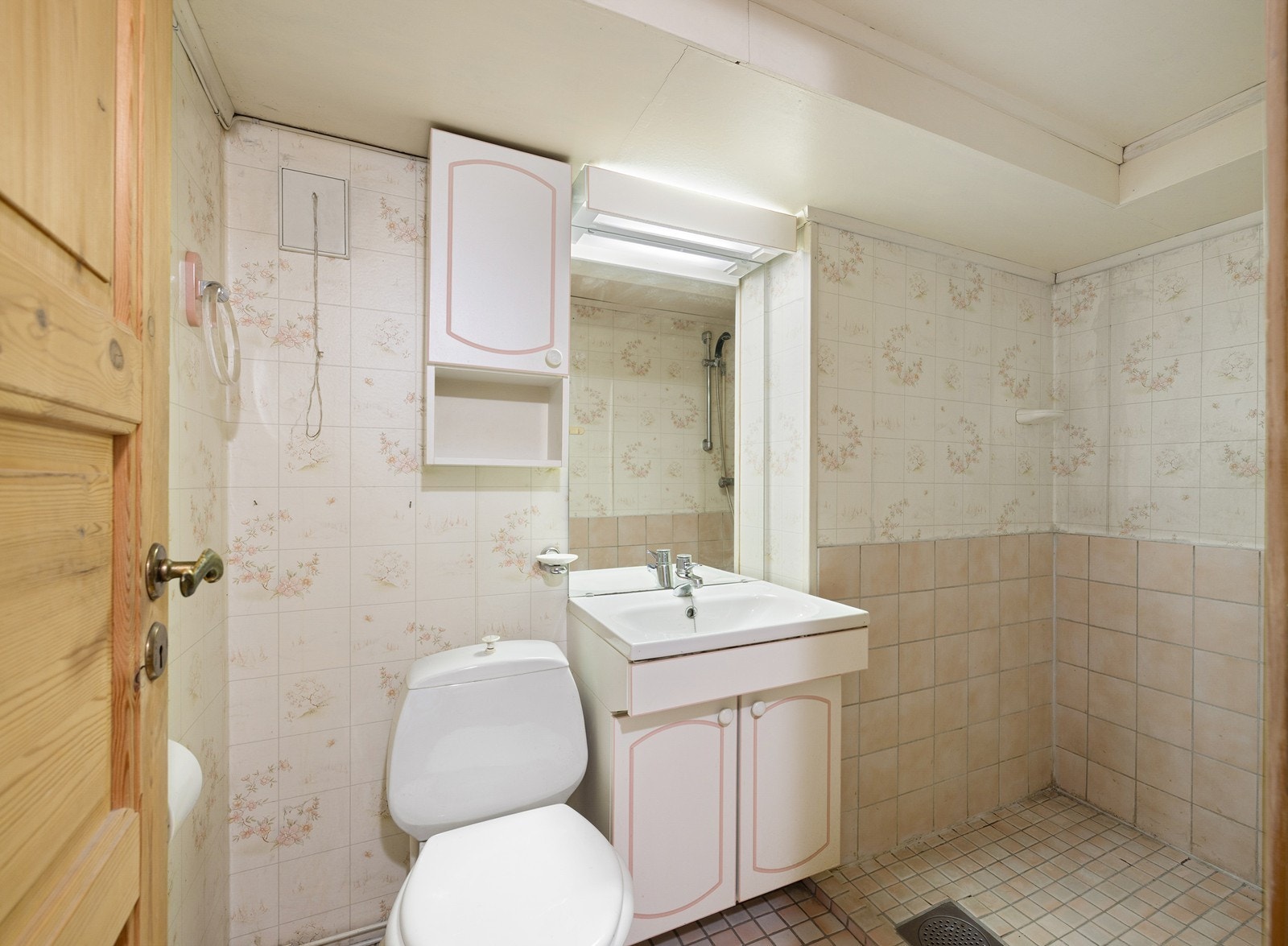 Badet i underetasjen har fliser på gulv og deler av veggene, samt tapetserte veggflater for øvrig. Innredningen består av et underskap, servant, speil, toalett og en dusjsone. Galleribilde