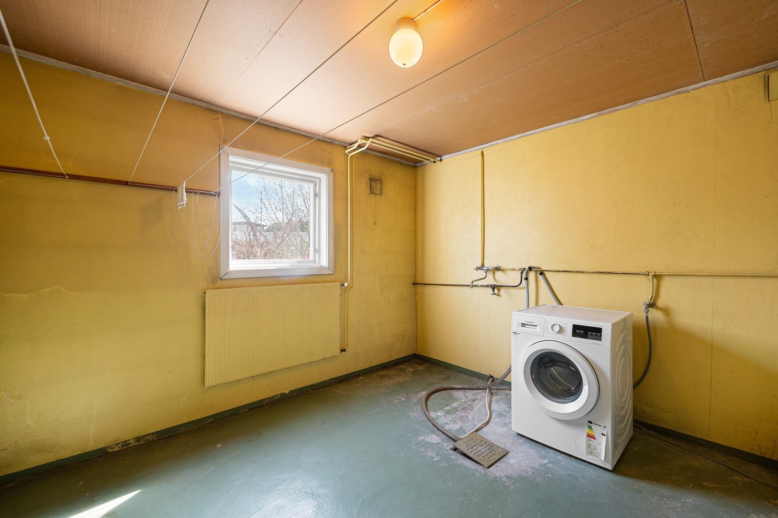 Etasjen har et praktisk vaskerom med malt betong på gulv og vegger. Rommet har opplegg for vaskemaskin, samt et eldre støpejernssluk i gulvet. Galleribilde