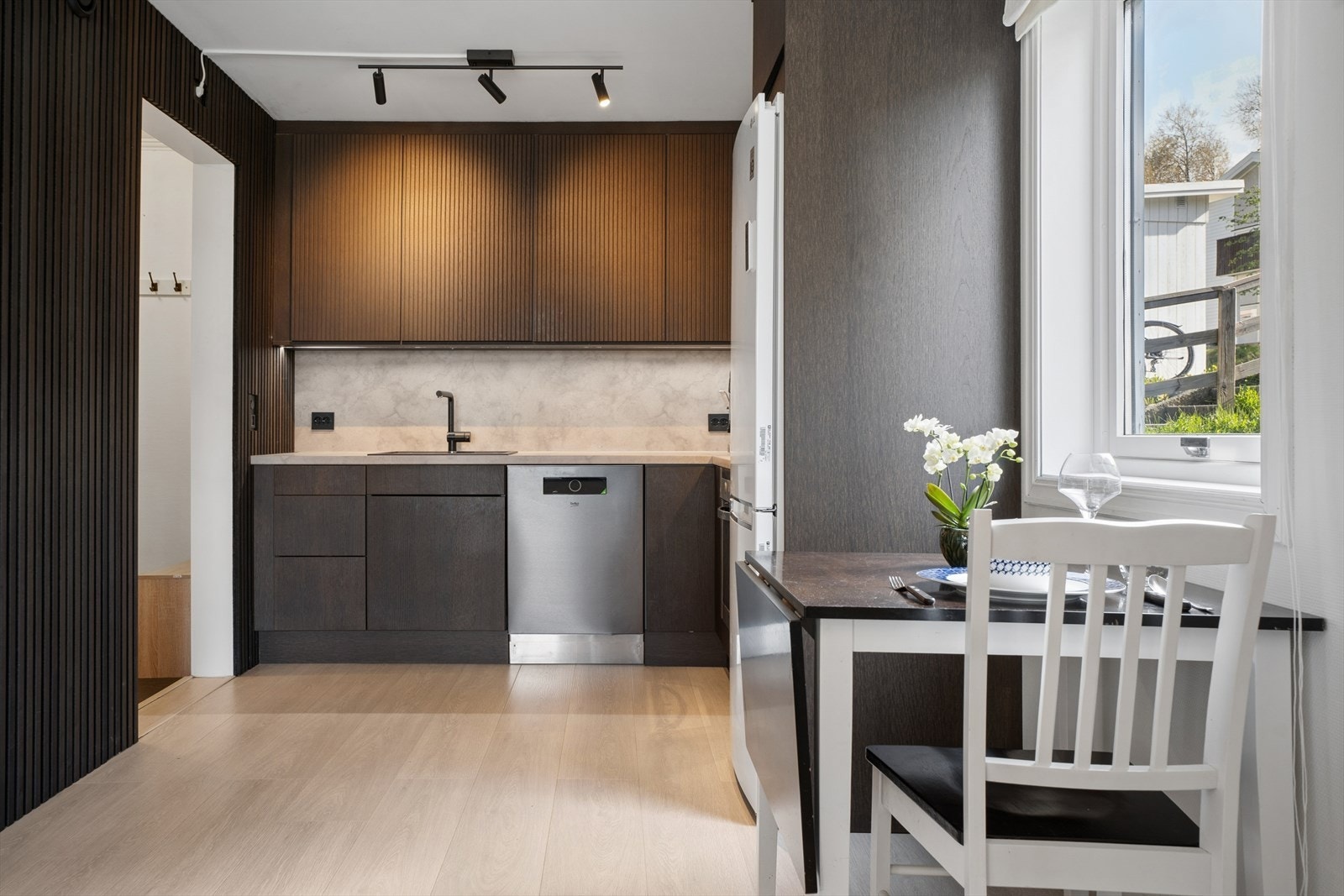 Kjøkkenet har en moderne innredning fra 2024, fra merket Epoc, med mørke, glatte fronter og laminat benkeplate med nedfelt kjøkkenkum i kompositt. Galleribilde