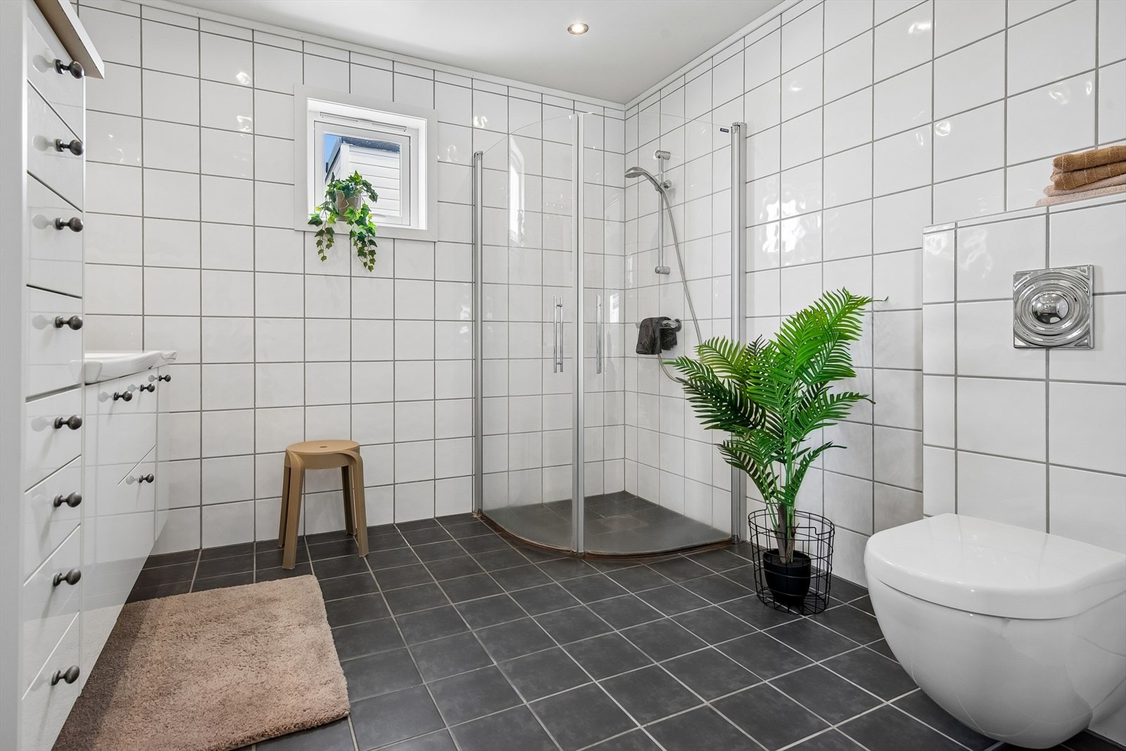 Badet i første etasje er flislagt og utstyrt med gulvvarme, vegghengt toalett og dusjvegger. Galleribilde