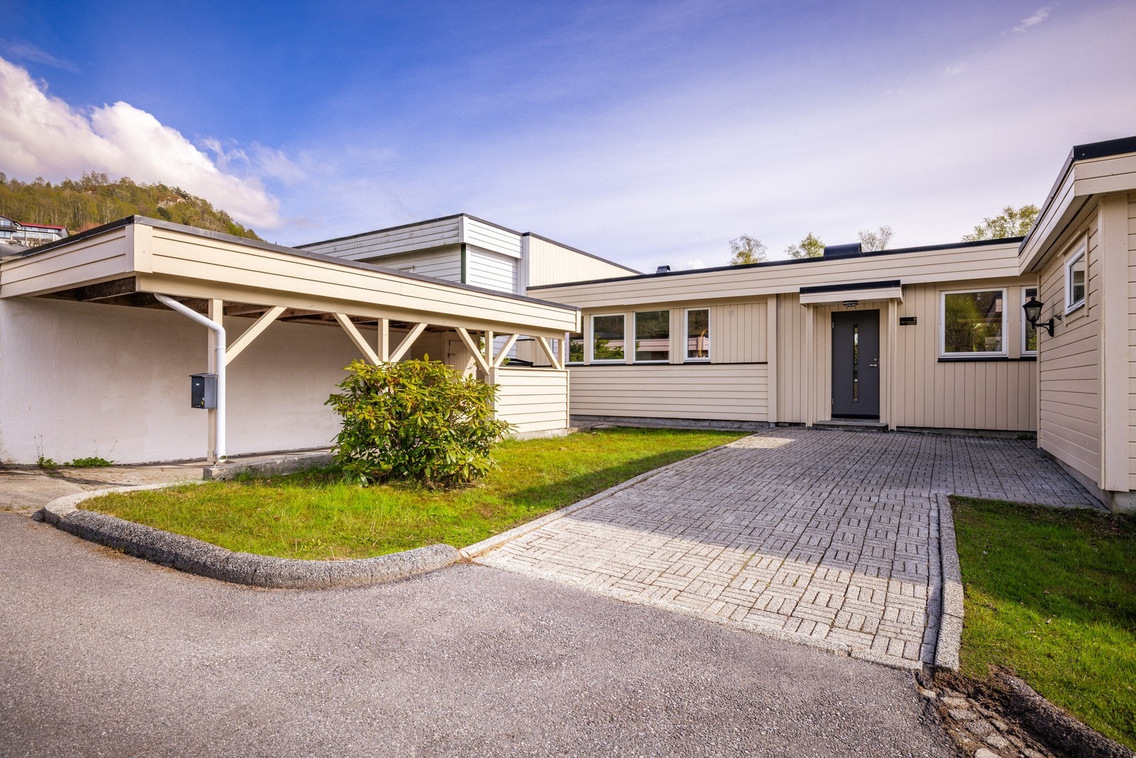 Eiendommen inkluderer en praktisk carport og utvendige boder for ekstra lagring. Galleribilde