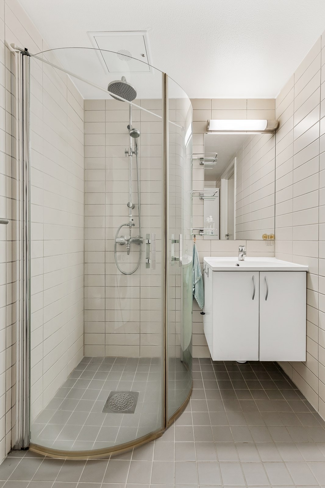 Badet er innredet med vegghengt servantinnredning og ovenpåliggende servant med ettgreps armatur. Over servanten er det speil og overlys med integrert stikkontakt. Det er dusjhjørne med dører og dusjbatteri tilkoblet veggmontert hånd- og regndusj. Galleribilde