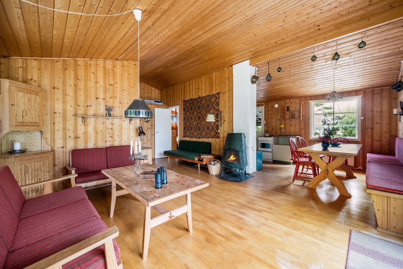 Vinkelstue med vedovn og plassbygd sofa ved spisebordet. Lagringsplass under sofa. Galleribilde