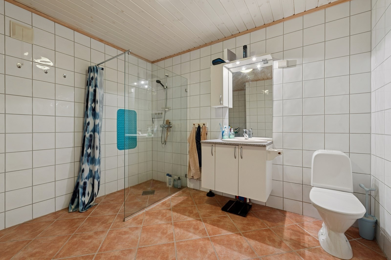 Funksjonelt, flislagt bad med dusjhjørne, WC og opplegg for vaskemaskin. Galleribilde