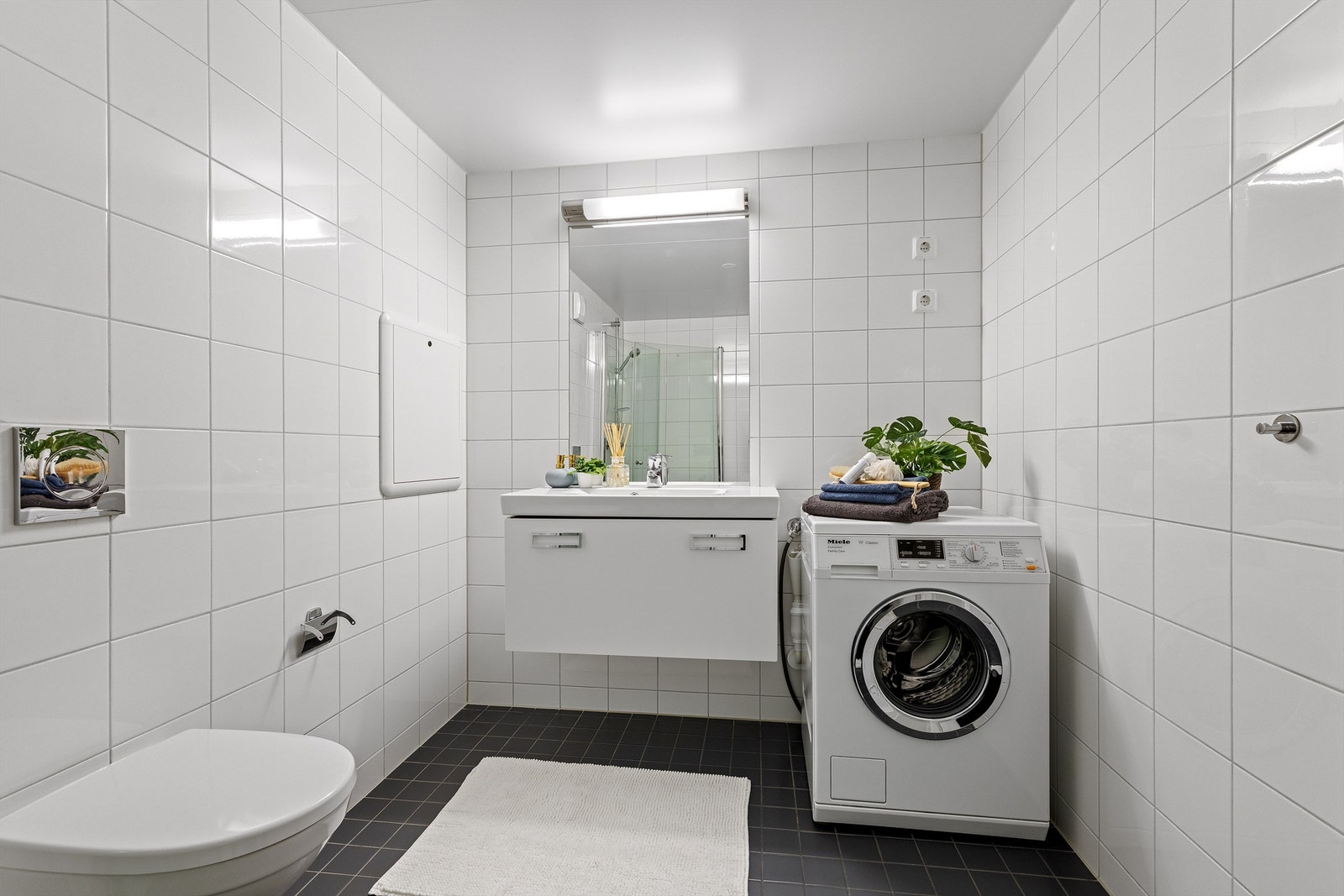 Badet har servantinnredning, speil med overlys og opplegg for vaskemaskin. Galleribilde