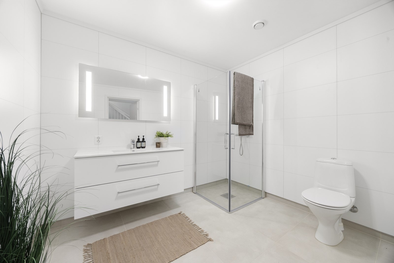 Badet er utstyrt med vegghengt toalett og et dusjhjørne med innfellbare glassdører som frigjør gulvplass. Galleribilde